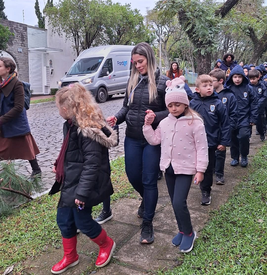 Alunos da escola em caminhada pela rua acompanhados por educadores