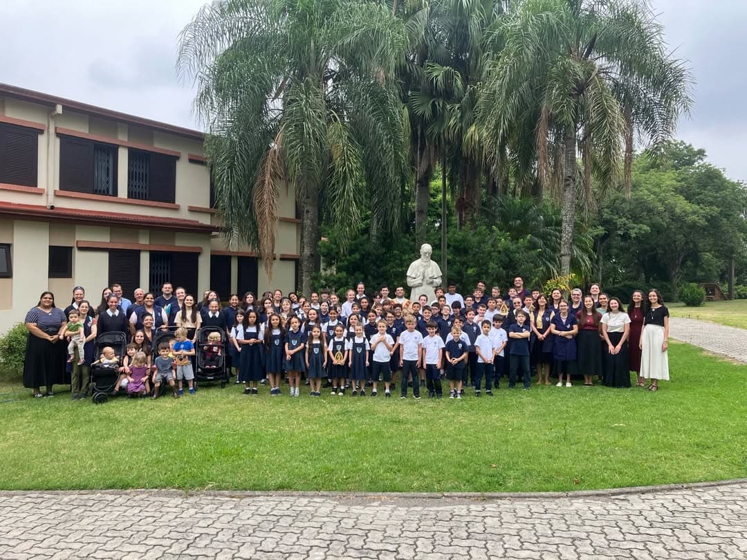 Comunidade escolar da Mater Educatrix reunida no gramado, com o prédio ao fundo